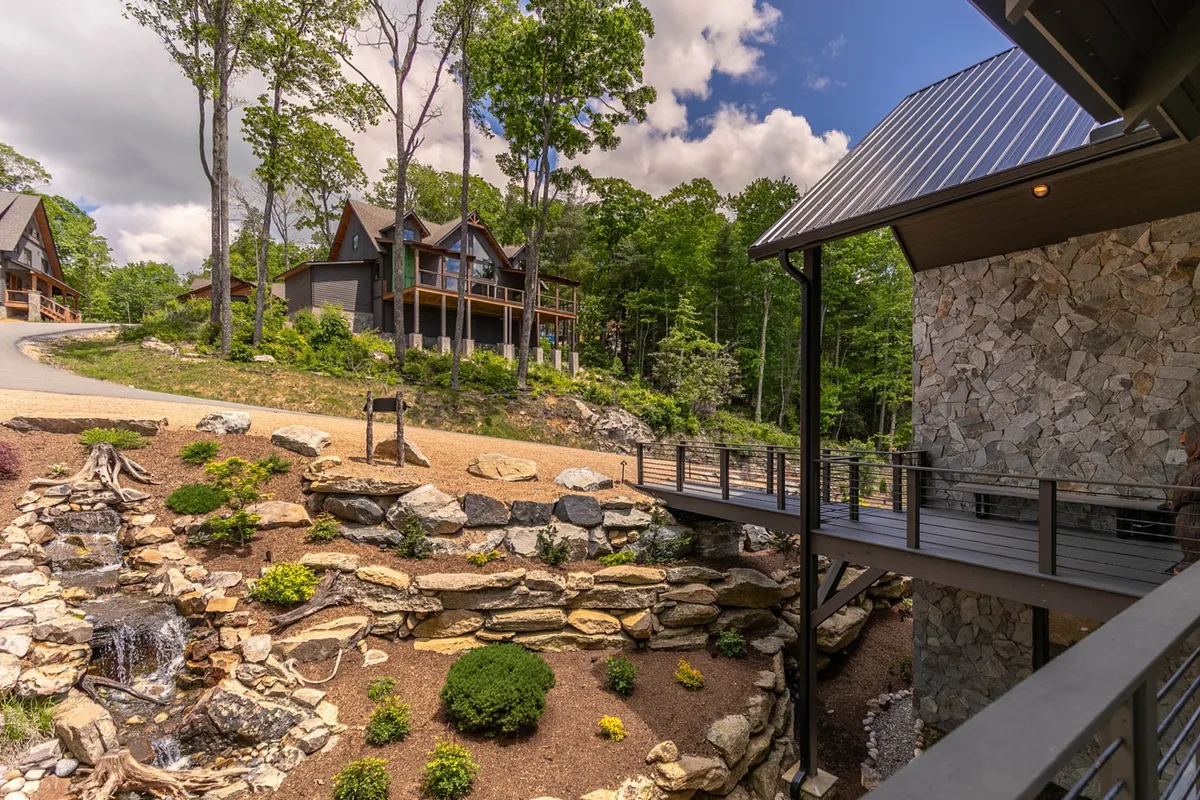 This image features a tranquil water feature set alongside a stone pathway, lush landscaped gardens, and striking modern architecture. The peaceful setting enhances the sensory experience of the outdoors.