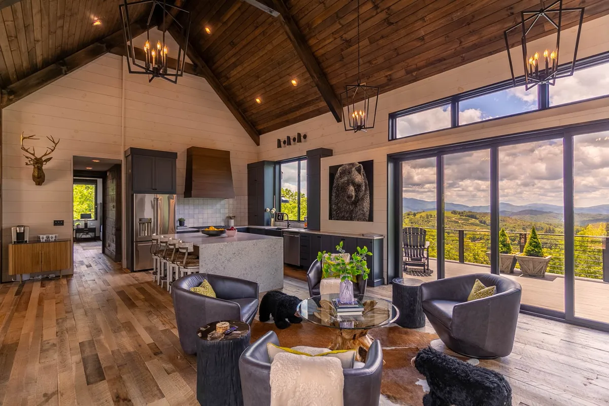 A stylish dining area with a central table, surrounded by large windows that maximize mountain views. Artistic wall decor and a plush seating area create a welcoming environment for shared meals or celebrations.