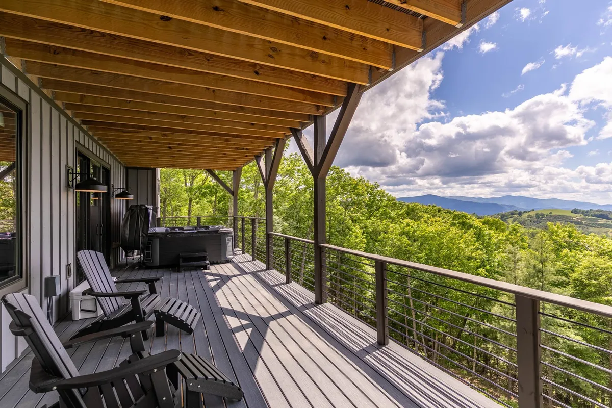 A wooden deck with a hot tub, outdoor seating, and panoramic mountain views. The setting is designed for relaxation and social gatherings, whether soaking under the stars, hosting a barbecue, or admiring the changing landscape through the seasons.