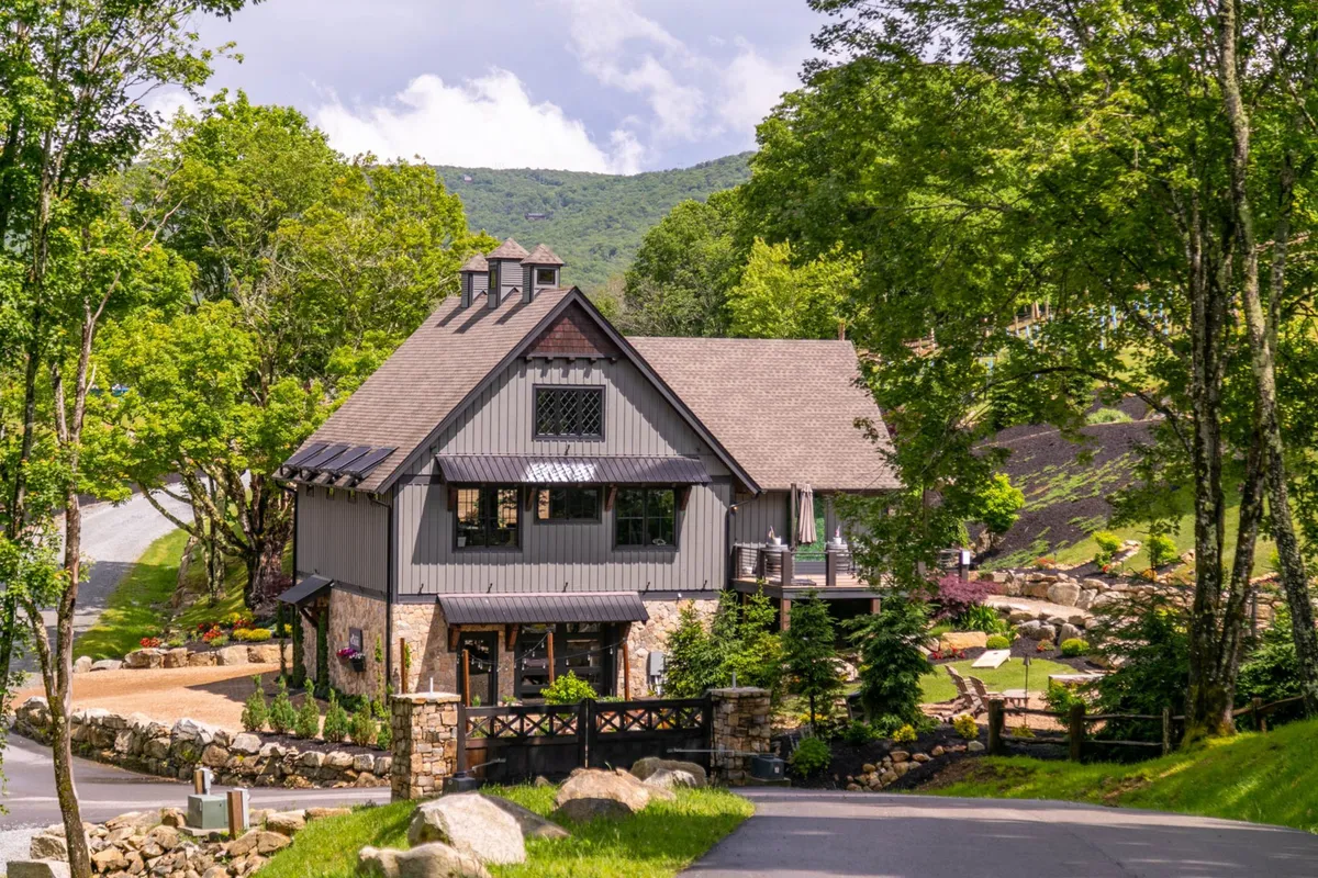 Featuring modern architectural elements, lush landscaping, stone accents, large windows, and a welcoming outdoor seating area, this image conveys a serene and vibrant environment for families to gather and participate in outdoor activities.