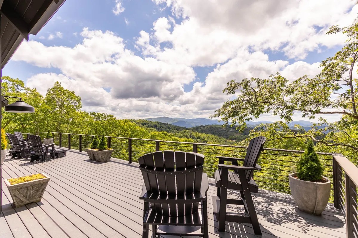 A serene exterior shot featuring deck chairs positioned to overlook a sweeping mountain view, with planters adding a touch of greenery. The scene is set for relaxation and social gatherings in nature, inviting guests to unwind and take in the scenery.